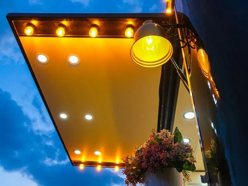 Lit awning of a coffee trailer at dusk